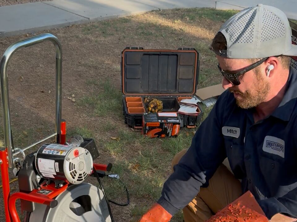 Mitch running a drain cleaning machine through an outdoor cleanout