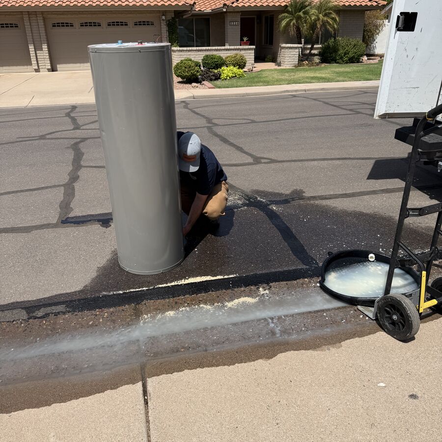 Old leaking 50-gallon electric water heater removed from a Dobson Ranch home in Mesa AZ, showing heavy mineral scale on the bottom