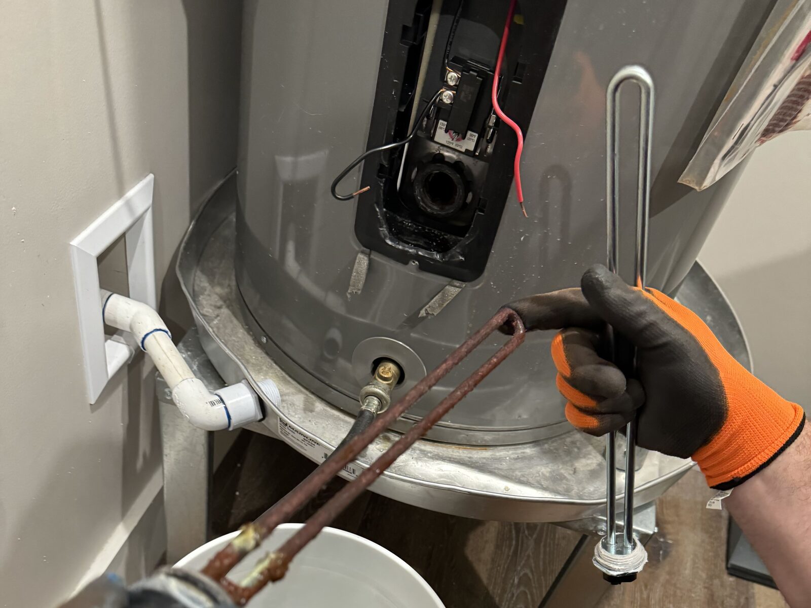 Water Pros Plumbing technician replacing a corroded heating element on a tank water heater in Gilbert AZ