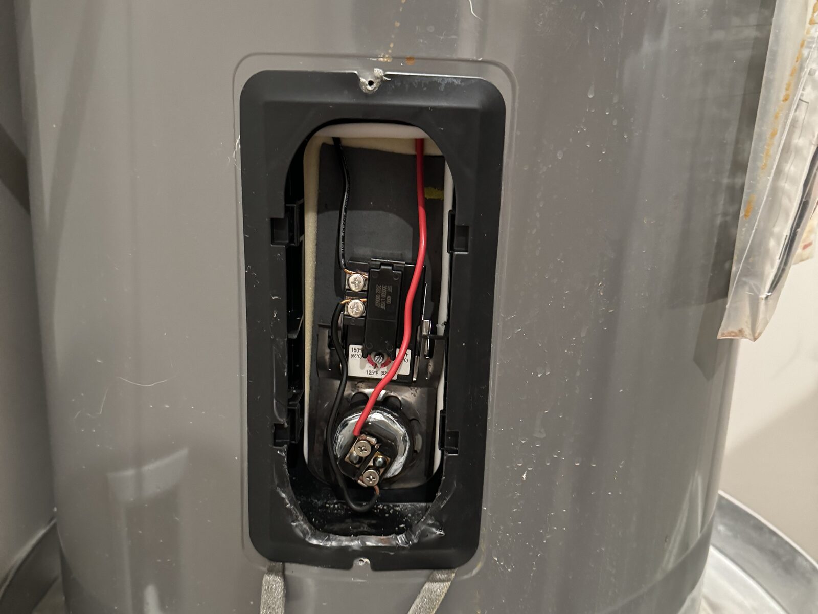 Open thermostat and access panel on a residential water heater during a repair in Gilbert AZ